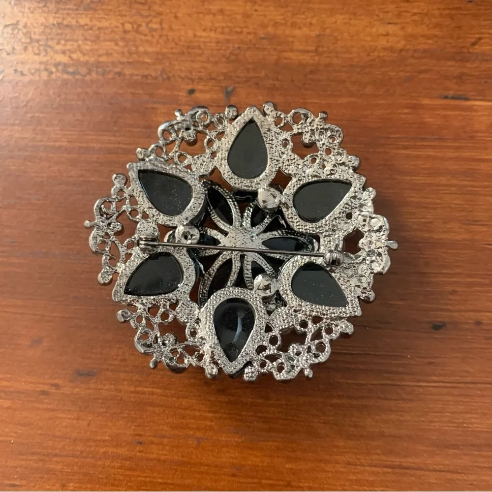 Black rhinestones flower brooch with silver tone filigree
